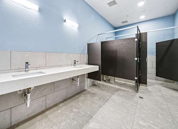 A public restroom with a row of sinks and a row of stalls.