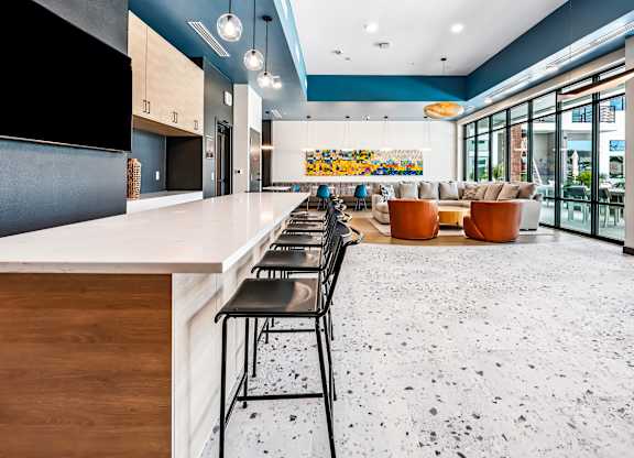 A modern kitchen with a long bar and chairs.