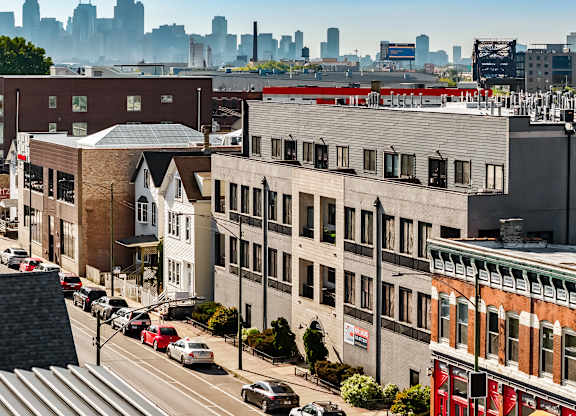 A city street with cars and buildings in the foreground with a city skyline in the background.