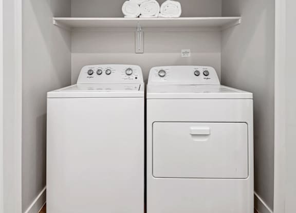 Two white washing machines in a laundry room.