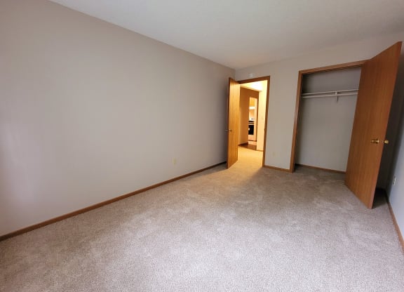 an empty bedroom with a closet and a door to a bathroom