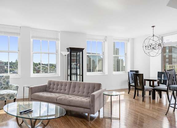 A living room with a grey sofa, a glass table, and a chandelier at Residences Providence, Providence, RI