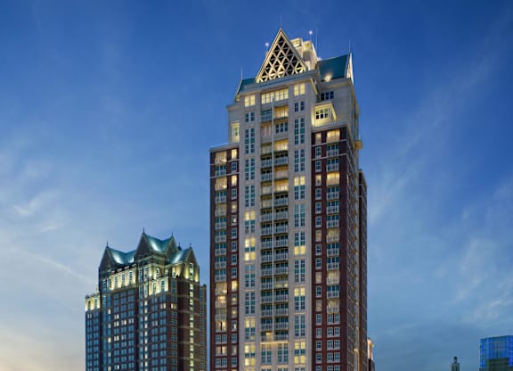 A tall building with a pointed top is lit up at dusk at Residences Providence, Providence