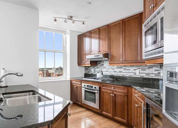 A modern kitchen with wooden cabinets and stainless steel appliances at Residences Providence, Providence, RI 2903