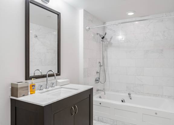 A bathroom with a white tiled shower and a white bathtub at Residences Providence, Providence, RI