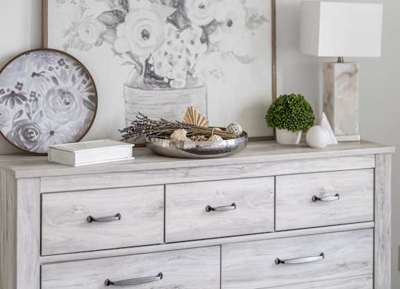 A white dresser with a framed picture of flowers on top and a small potted plant to the right at Residences Providence, Providence, RI 2903