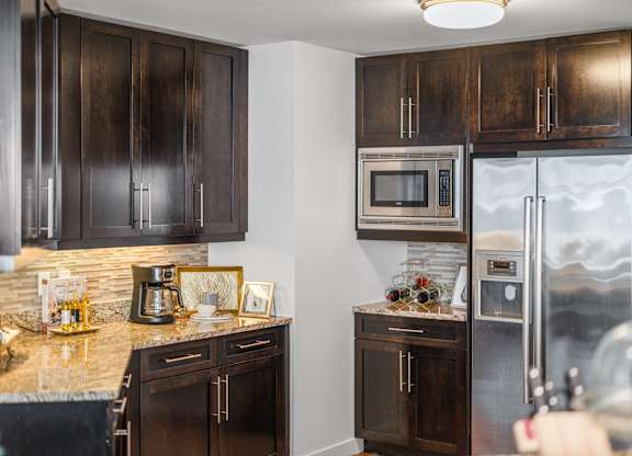 A kitchen with dark wood cabinets and stainless steel appliances at Residences Providence, Rhode Island