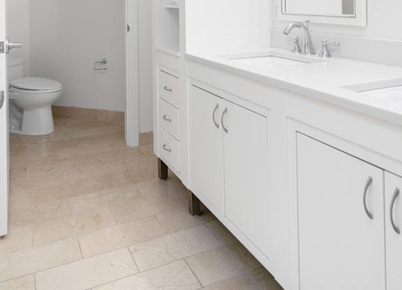 A white bathroom with a toilet, sink, and medicine cabinet at Residences Providence, Providence, RI