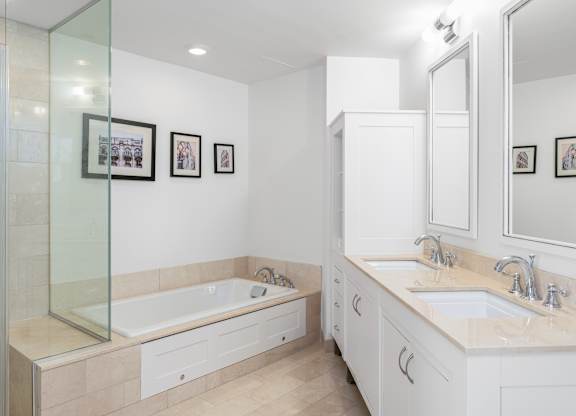 A bathroom with a glass shower door and a white bathtub at Residences Providence, Providence