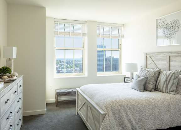 A bedroom with a large bed and a dresser with a plant on top at Residences Providence, Providence, Rhode Island
