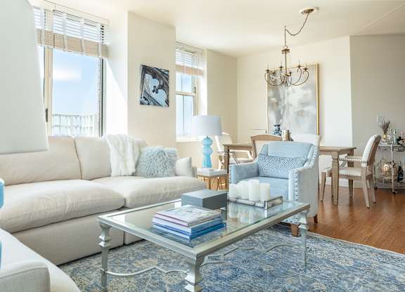 A living room with a white couch, a glass coffee table, and a chandelier at Residences Providence, Rhode Island 2903