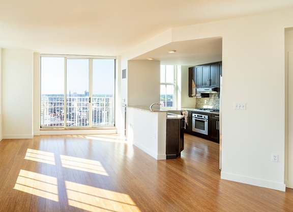 A large open living room with wooden floors and a balcony with a view of the city at Residences Providence, Rhode Island 2903
