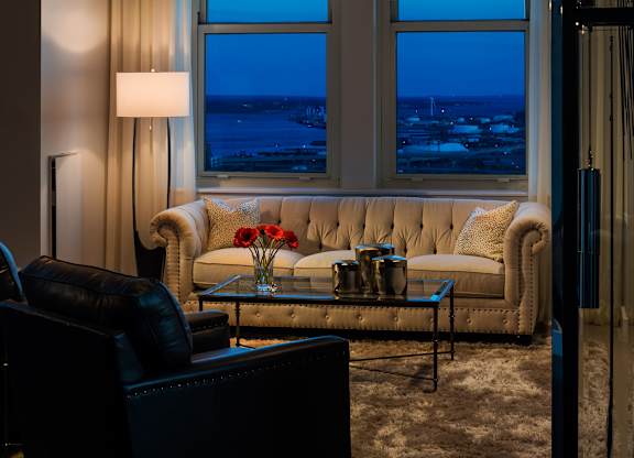 A living room with a couch, coffee table, and a view of the city at night at Residences Providence, Providence, RI