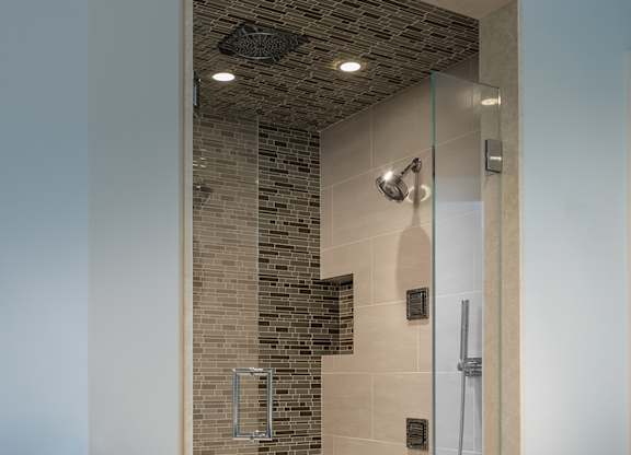 A bathroom with a glass shower door and a brown towel hanging on the wall at Residences Providence, Providence