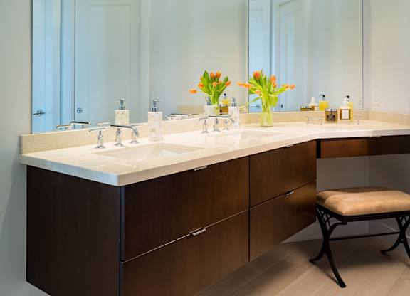 A modern bathroom with a vanity, a mirror, and a chair at Residences Providence, Rhode Island
