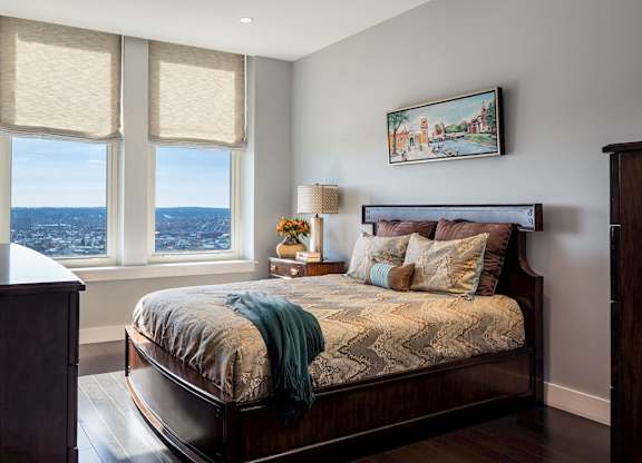 A bedroom with a large bed and a view of the city through the window at Residences Providence, Rhode Island