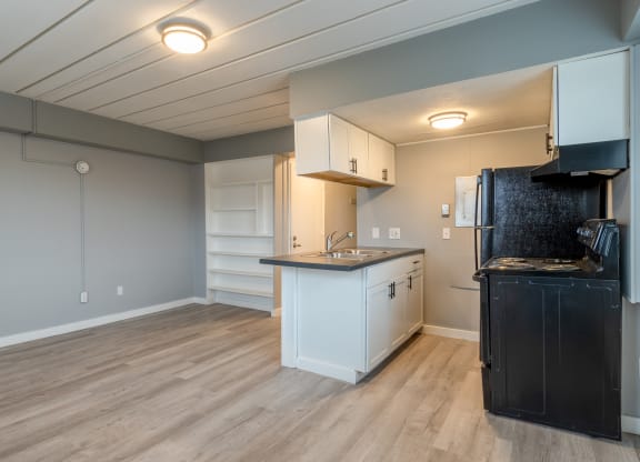 a kitchen with white cabinets and a counter top and a black refrigerator