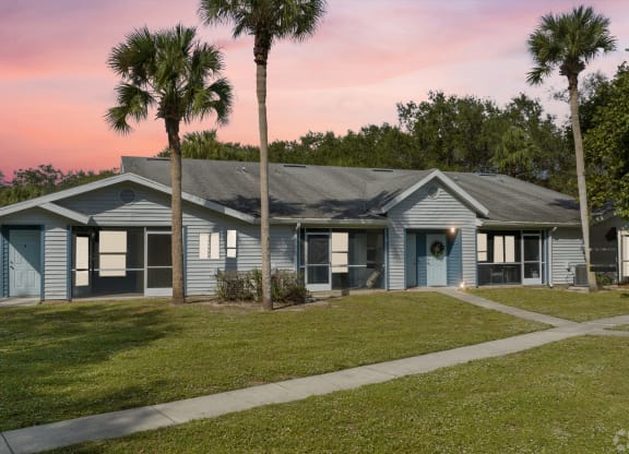 a blue house with palm trees in front of it at Aqua Bay Apartments in Naples, FL 34116