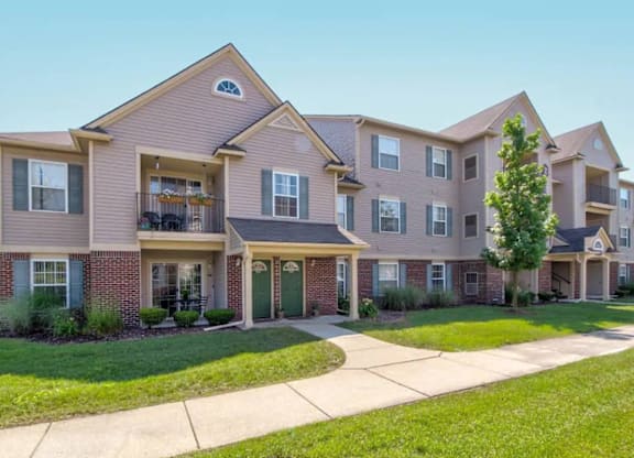A large, multi-story apartment building with a green lawn in front.