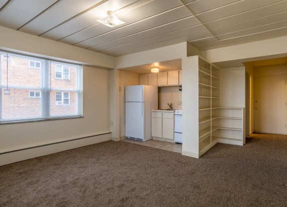 an empty room with a kitchen and a window