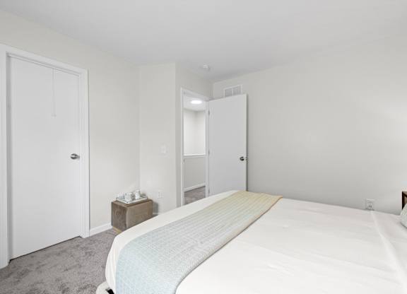 A bedroom with a large bed and two doors.