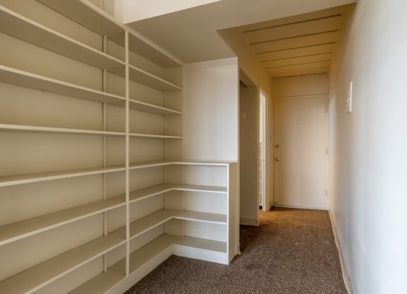a walk in closet in a house with empty shelves