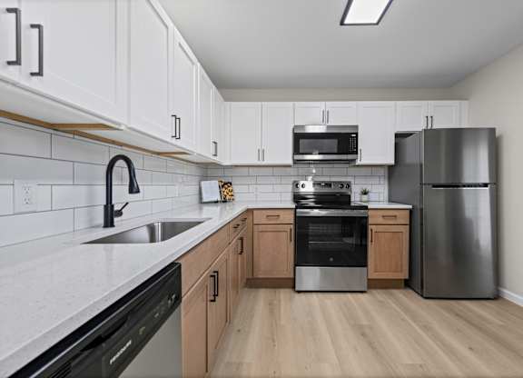 A kitchen with a black dishwasher and stove top oven.
