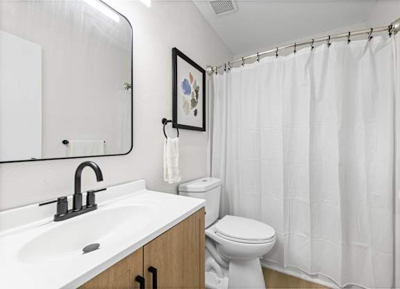 A white bathroom with a toilet, sink, and shower curtain.