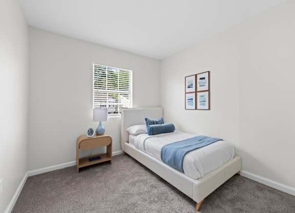 A bedroom with a bed, nightstand, and window.