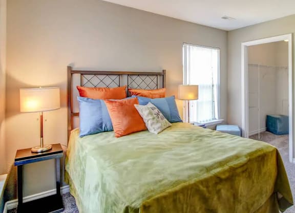 A bedroom with a bed, nightstand, and window.