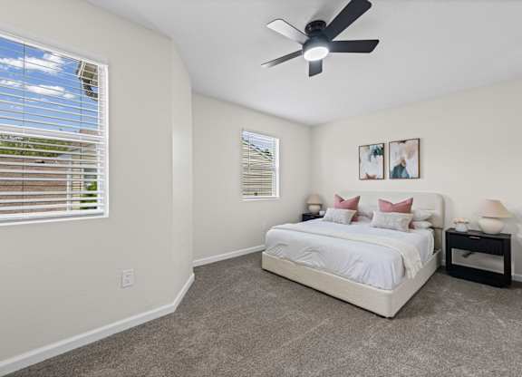 A bedroom with a bed, nightstand, and a ceiling fan.
