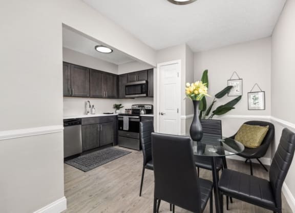a dining area with a table and chairs and a kitchen in the background