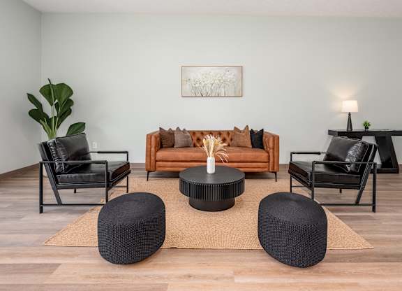A living room with a brown sofa, black chairs, and a coffee table.