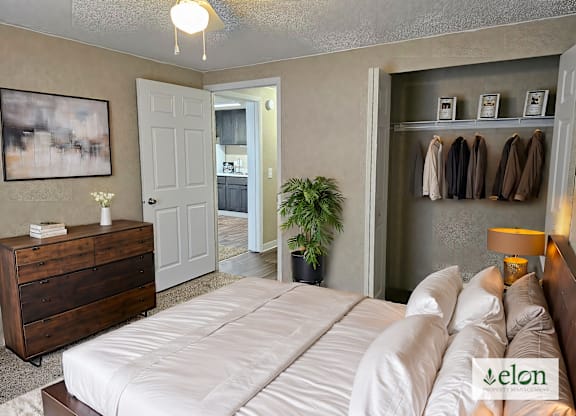 A bedroom with a bed, dresser, and coat rack.
