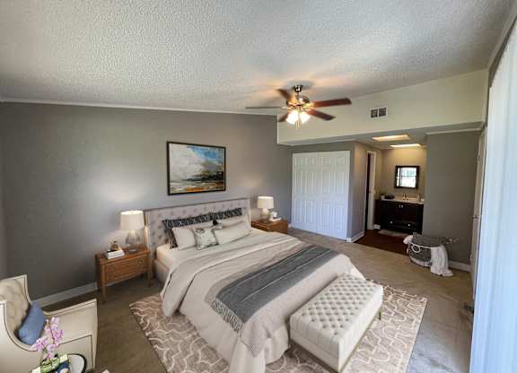 A bedroom with a large bed and a ceiling fan.