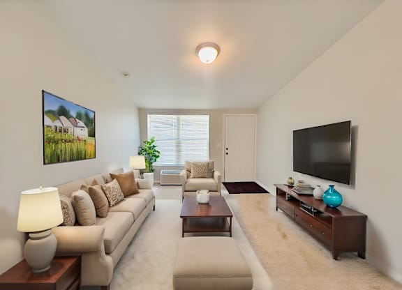 A living room with a beige sofa, a coffee table, and a flat screen TV.