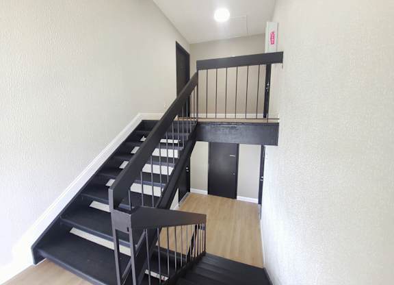 A staircase with a black railing and steps leading to a door.