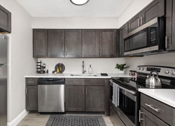 a kitchen with dark cabinets and stainless steel appliances