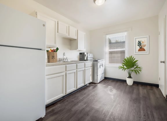 a white kitchen with white cabinets and a white refrigerator