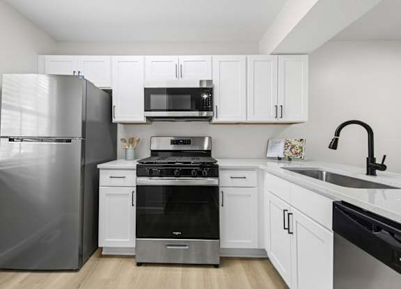 A modern kitchen with white cabinets and stainless steel appliances.