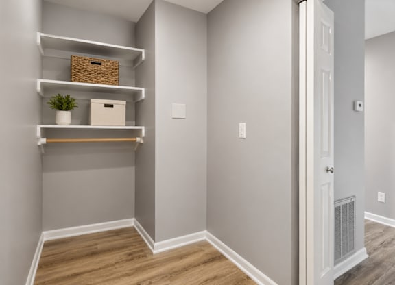 A room with a white door and shelves with a plant and a basket on them.