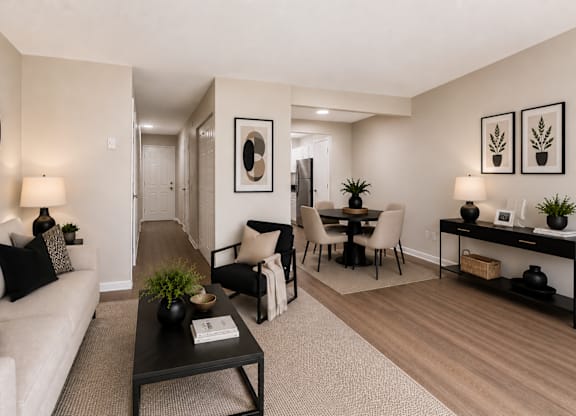 A living room with a white couch, a black coffee table, and a dining area with a table and chairs.
