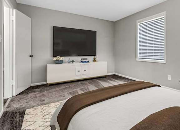 A bedroom with a large bed and a flat screen TV mounted on the wall.