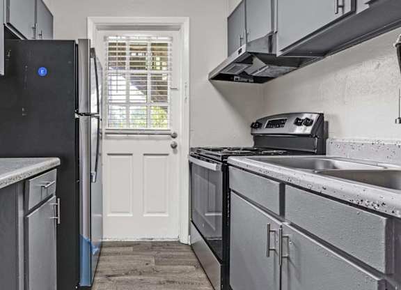 A kitchen with a black fridge and a white door.