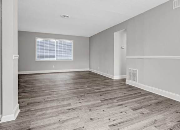 A room with wooden flooring and a window with blinds.