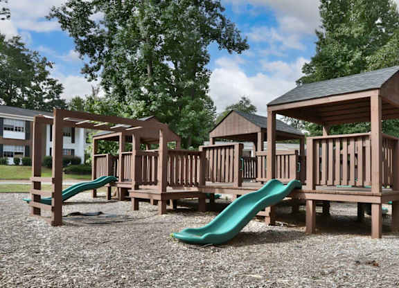 A playground with wooden structures and green slides.