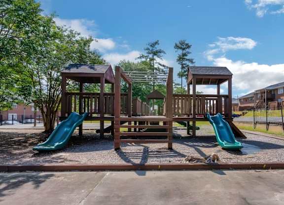 A playground with a green slide and a brown wooden structure.