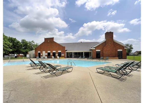Outdoor pool area with several lounge chairs surrounding the pool. 