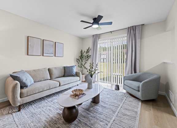 A living room with a grey couch, a coffee table, and a ceiling fan.