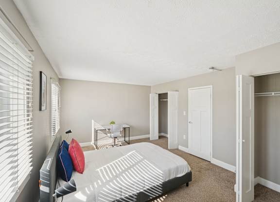 A bedroom with a bed, a chair, and a small table with a plant on it.